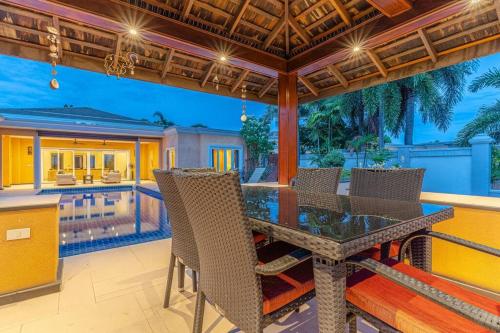 an outdoor dining area with a table and chairs at Pattaya Luxury 4BR Pool Villa-BBQ, Karaoke & Pool Table for Families & Group of Travellers in Nong Prue