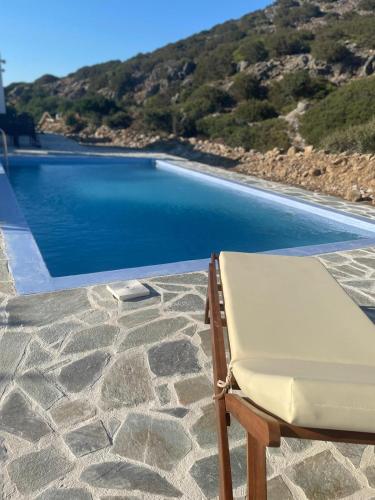a chair sitting on a patio next to a pool at Villa Edna Crete in Agios Nikolaos