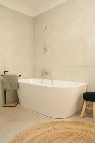 a white bath tub in a bathroom with a stool at Sunshinewilla com - amazing sea view - private pool - 4 bedrooms - 3 bathrooms - workout in Kaštelir