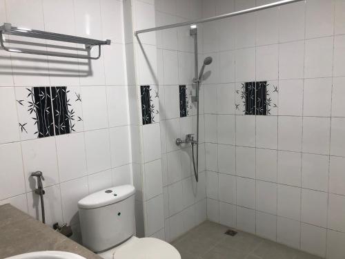 y baño de azulejos blancos con aseo y ducha. en The G Ten Holiday Inn en Hulhumale