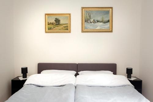 two beds in a bedroom with two pictures on the wall at Apartament Ada in Sopot