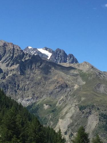 Une montagne avec de la neige au sommet dans l'établissement PUY SAINT VINCENT APPARTEMENT T2 BALCON SUPER PANORAMA AVEC PARKING PRIVE COUVERT et PISCINE L'ETE, à Puy-Saint-Vincent