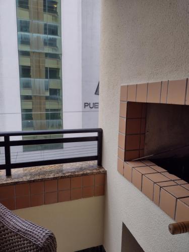 a balcony with a brick fireplace next to a building at Apartamento Balneário Camboriú in Balneário Camboriú