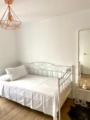 a white bed in a white bedroom with a mirror at La casita de Lú in Casares