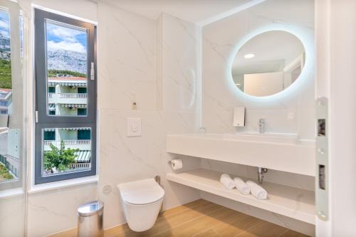 a white bathroom with a sink and a mirror at Aparthotel Remaneo in Promajna