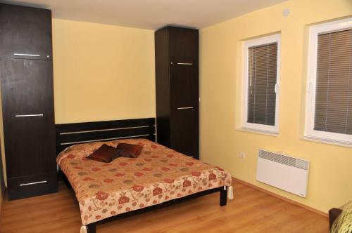 ein Schlafzimmer mit einem Bett und zwei Fenstern in der Unterkunft Chanovi apartments in Ohrid