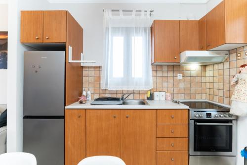 a kitchen with wooden cabinets and a stainless steel refrigerator at Παραθαλάσσια κατοικία με μπάρμπεκιου και τζακούζι in Stavros