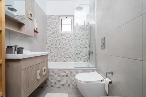 a bathroom with a toilet and a sink and a tub at Παραθαλάσσια κατοικία με μπάρμπεκιου και τζακούζι in Stavros