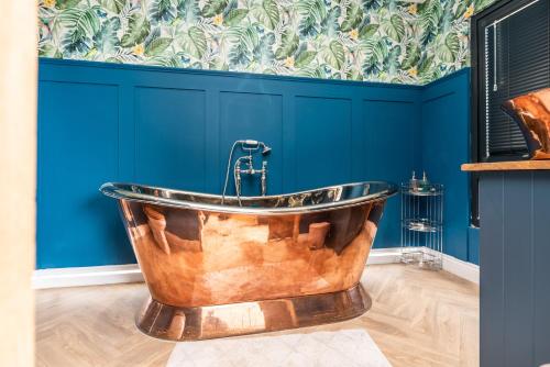 a large copper tub in a bathroom with blue walls at Brandy cove in Swansea