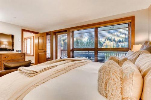 a bedroom with a large white bed with windows at Luxury Ski In, Ski Out 3 Bedroom Mountain Residence In The Heart Of Lionshead Village With Heated Slope Side Pool And Hot Tub in Vail