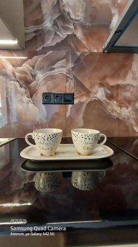 two coffee cups on a table in front of a wall at My Zen Apartment (Κεντρικό, ήσυχο, πολλές παροχές) in Preveza