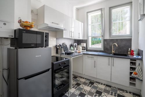 a kitchen with white cabinets and a black refrigerator at SUPERLOGIS L'Alysse Classé 3étoiles HYPERCENTRE BLOIS in Blois