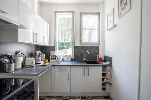 a kitchen with white cabinets and a sink at SUPERLOGIS L'Alysse Classé 3étoiles HYPERCENTRE BLOIS in Blois