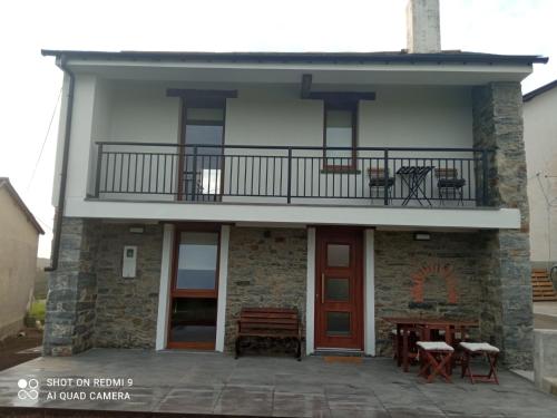 a building with a balcony and a table and benches at La Casina de Tano (Playa Tauran) in Luarca