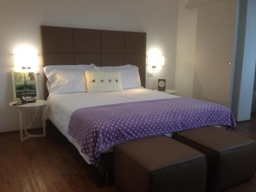 a bedroom with a large bed with a purple comforter at Hotel Piero Della Francesca in Arezzo