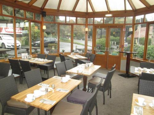 a restaurant with wooden tables and chairs and windows at Laird And Dog Inn in Lasswade