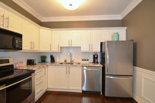 a kitchen with white cabinets and a stainless steel refrigerator at The SoMa Furnished Residences in Hamilton