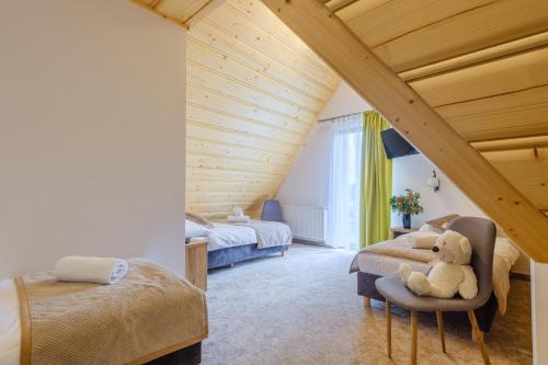 - une chambre avec deux lits et un ours en peluche assis sur une chaise dans l'établissement Suchowianka Ski&Relax, à Białka Tatrzańska