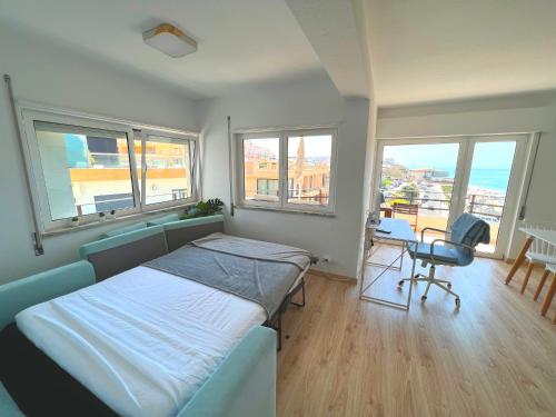 um quarto com uma cama, uma secretária e janelas em Apartamento Frente Mar Praia da Areia Branca em Praia da Areia Branca