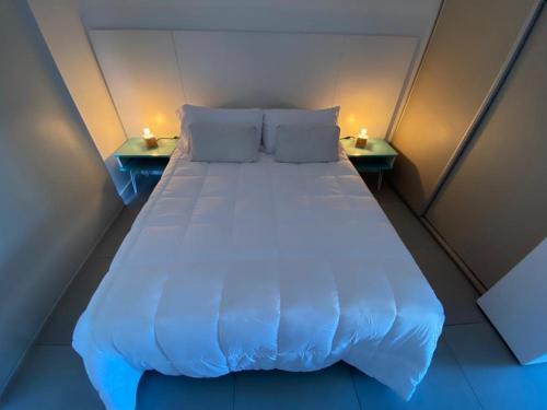 1 cama grande en una habitación pequeña con 2 mesas en departamento San Carlos en Mar del Plata