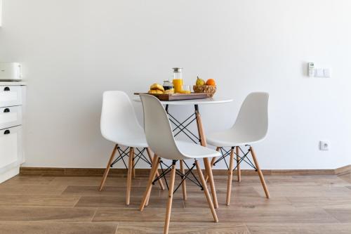 - une table à manger avec 4 chaises blanches dans l'établissement Casa dos Copos - Drinks House, à Miranda do Corvo