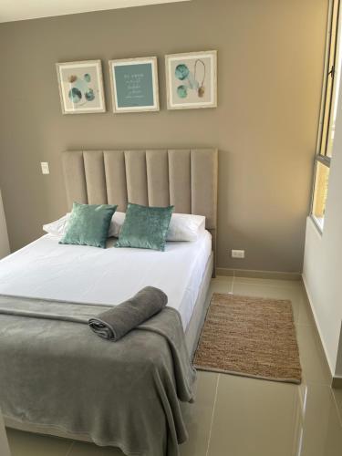 1 dormitorio con 1 cama blanca grande con almohadas verdes en LD House luxury, en Cali