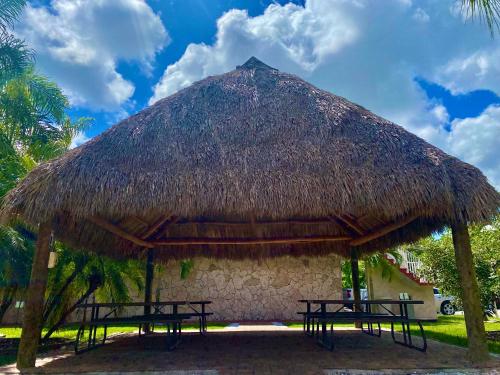 a straw hut with two picnic tables in it at Garden Inn Homestead/Everglades/Gateway to Keys in Homestead