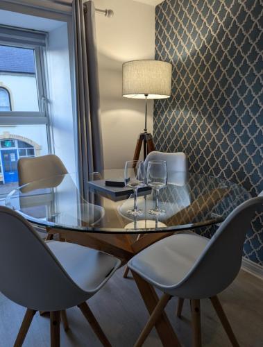 a dining room table with chairs and a lamp at Antrim Coast Apartments in Cushendall
