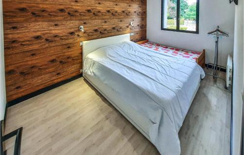 a large bed in a room with a wooden wall at Gorgeous Home In Bacilly With Kitchen in Bacilly