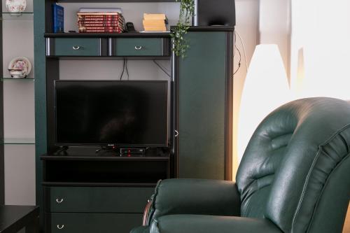 a living room with a leather chair and a television at Isabel Dream IV, 400m from the train in Mem Martins