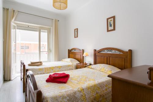 ein Schlafzimmer mit 2 Betten und einem Tisch mit einer roten Tasche darauf in der Unterkunft Isabel Dream IV in Algueirão-Mem Martins