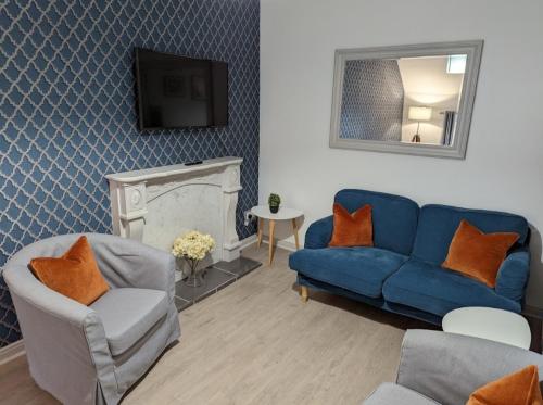 a living room with a blue couch and a tv at Antrim Coast Apartments in Cushendall