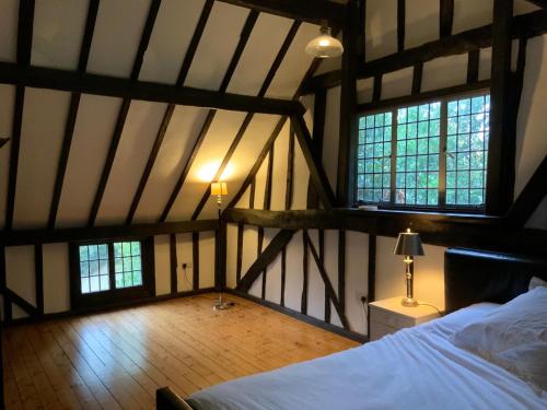 エデンブリッジにあるDelightful 4BD Home full of Flair Edenbridge Kentのベッド1台と窓2つが備わる屋根裏部屋です。