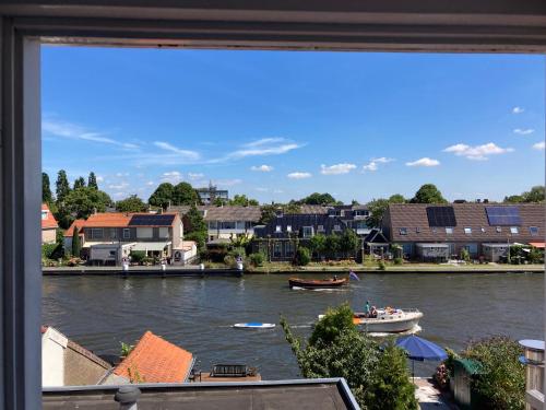 a view from a window of a river with boats at Luc's place, Waterbed grote kamer in Zoeterwoude