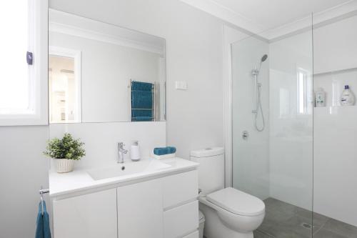 a white bathroom with a toilet and a shower at Camellia Cottage in Berrima