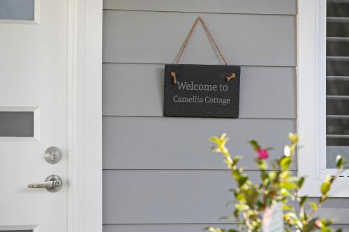 una puerta con una señal que diga bienvenida al cáncer de Cranfield en Camellia Cottage en Berrima