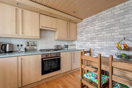 een keuken met houten kasten en een fornuis met oven bij Centrally Situated 1 Bedroom House in Cumbernauld in Cumbernauld