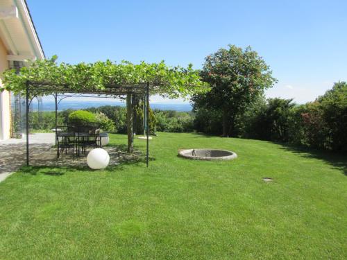 a garden with a pergola and a table in the grass at B&B Pension Marina in Rüttenen  