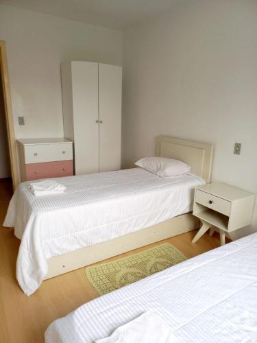 a bedroom with two beds and a dresser and a night stand at Serra Gaúcha Uva e Vinho 102 in Bento Gonçalves