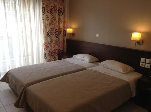 2 Betten in einem Hotelzimmer neben einem Fenster in der Unterkunft Hotel Electra in Volos