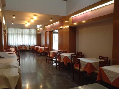 een eetkamer met tafels en stoelen met witte tafelkleden bij Hotel Electra in Volos