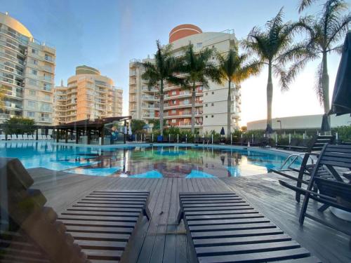 une grande piscine avec des palmiers et des bâtiments dans l'établissement Espetacular vista do mar - Beto Carrero - Ap502, à Penha