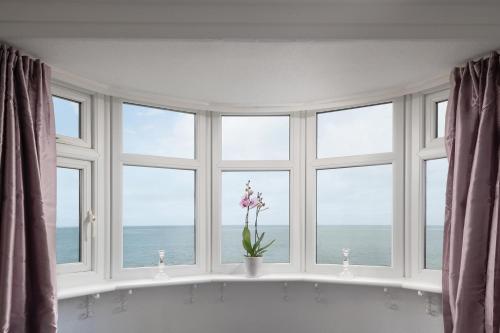 a room with a large window with a bath tub and flowers at Beachcliffe House - Sea front property - Sleeps 10 - Pet friendly in Llandrillo-yn-Rhôs