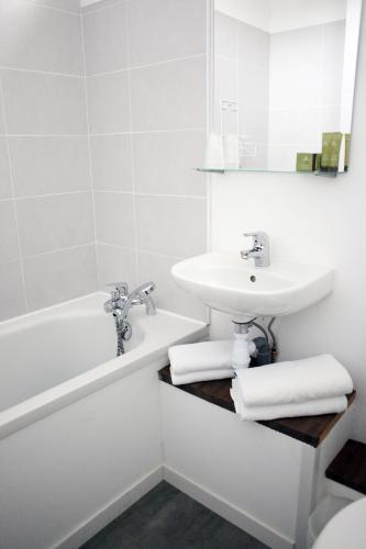 Un baño blanco con lavabo y bañera. en Hôtel Restaurant Gédéon, en Carnon-Plage