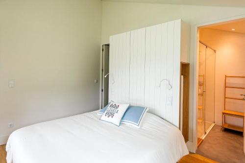 a bedroom with a white bed with a book on it at Sete Cidades Lake Cabin - Casa da Lagoa in Ponta Delgada