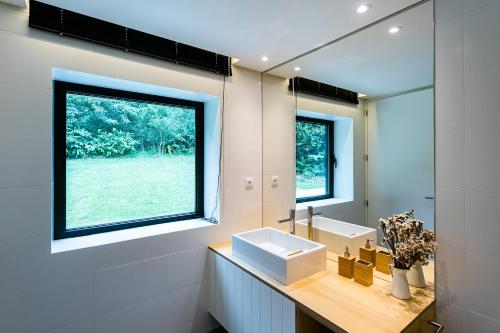 uma casa de banho com um lavatório e uma grande janela em Sete Cidades Lake Cabin - Casa da Lagoa em Ponta Delgada