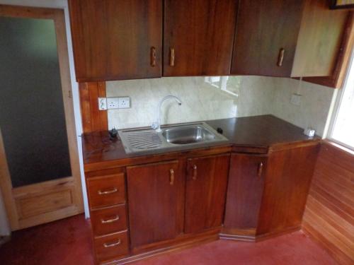 una cocina con armarios de madera y fregadero en Paradise Cottage Kandy, en Kandy