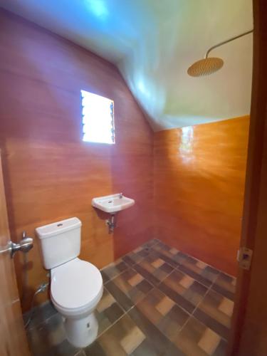 a bathroom with a toilet and a sink at Don Roberto's Kubo Resort in Nasugbu