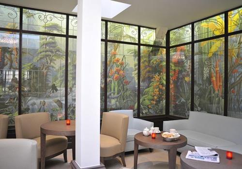 a room with tables and chairs and a stained glass window at Hotel de L'Universite in Paris