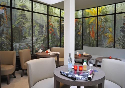 a dining room with tables and chairs and windows at Hotel de L'Universite in Paris